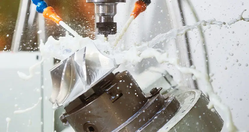 Close-up of CNC machine cutting metal with coolant spray for mechanical industry applications