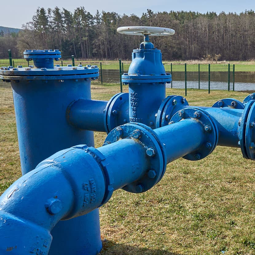 Industrial stainless steel tanks and pipes inside a modern beverage or food processing plant with blue-toned lighting.