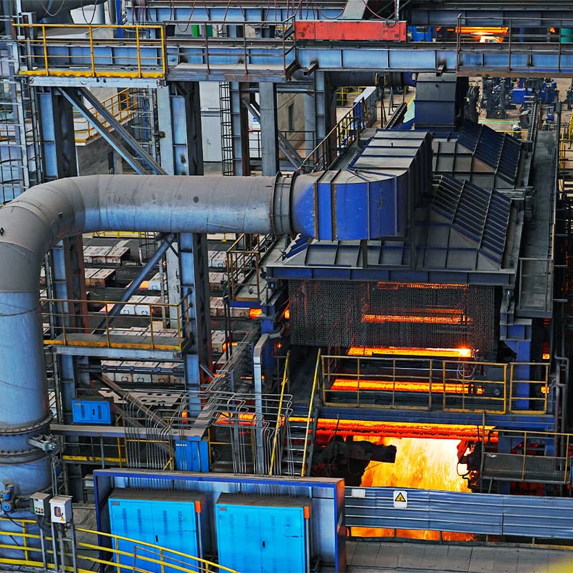 Industrial facility with machinery processing glowing molten metal.